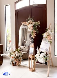 flowers are arranged in front of an open door with a sign on the floor next to it