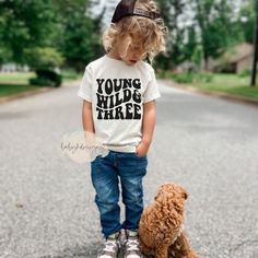 a little boy standing next to a brown dog on top of a skateboard in the street