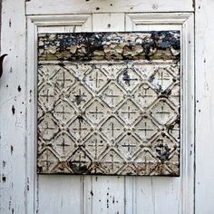 an old door with peeling paint on it and a rusted metal grate in the middle