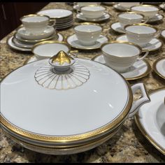 a table topped with lots of white and gold dishes