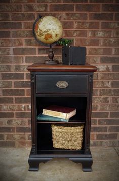 a book shelf with books and a globe on top, next to a brick wall