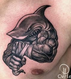 a man's chest with a shark tattoo on it and his arm holding a fist