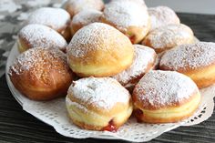 a white plate topped with powdered sugar covered donuts on top of a table