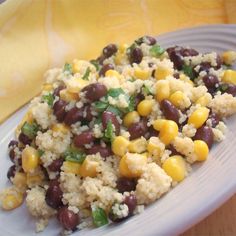 a white plate topped with black beans and corn next to a banana on a table