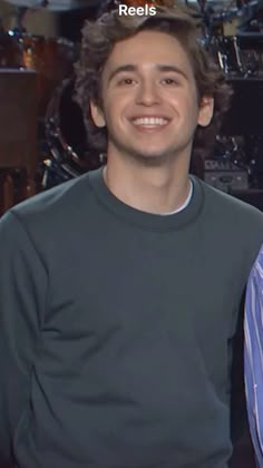 a smiling young man sitting in front of a drum set with the words reelies on it