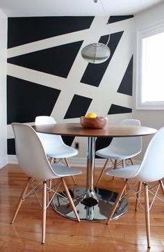 a dining room table with four chairs and a bowl of fruit on top of it