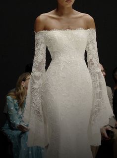 a woman in a white wedding dress with long sleeves and an off - the - shoulder top