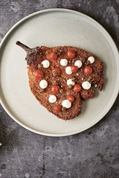 a white plate topped with two pieces of meat covered in cheese and tomato toppings