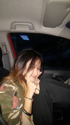 a woman sitting in the back seat of a car with her hand on her face