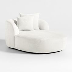 a white couch with pillows on top of it in front of a white wall and floor