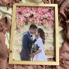 a wooden frame with a photo of a bride and groom in front of pink flowers