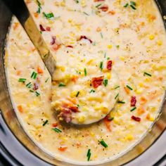 a spoon in a bowl filled with corn chowee and garnished with scallions