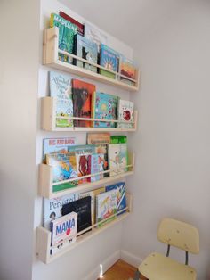 the bookshelf is filled with children's books and has two chairs in front of it