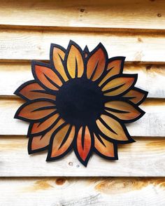 a metal sunflower sitting on top of a wooden wall