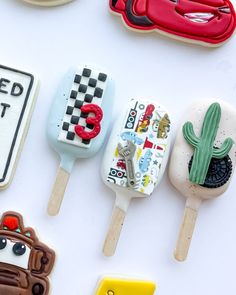 decorated cookies are arranged in the shape of cars, trucks and road signs on sticks