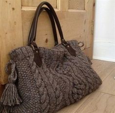 a handbag sitting on the floor in front of a door with a wooden handle