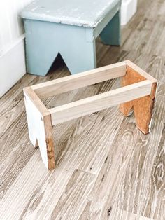 a wooden bench sitting on top of a hard wood floor next to a blue stool