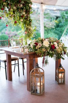 a table with flowers and candles on it under a tented area for an outdoor wedding