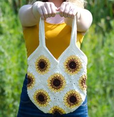 a woman holding onto a crocheted bag with sunflowers on the front