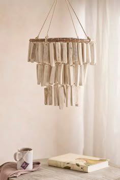 a chandelier hanging from the ceiling over a table next to a book and cup