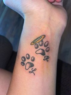 a person with a tattoo on their arm and paw prints around the wrist that has a frisbee in it