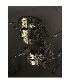 This couple's masquerade mask set is new for 2023.  Masks are hand painted black and accented with a matching gold stripe.  Both masks are made of a flexible lightweight metal and come with black silk ribbon ties attached.  This couple's mask set is great for any Masquerade ball or costume mask party!  Masks are also available in black with silver stripe, black with bronze stripe, and black with red stripe upon request.   Women's mask size 8"W x 7.5H Men's mask size 6.5"W x 7"H