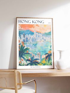 a white vase sitting on top of a wooden table next to a framed hong kong poster