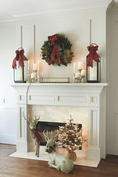 a fireplace decorated for christmas with candles, wreaths and deer figurines on the mantel