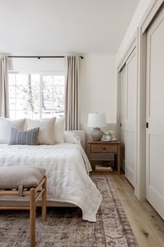 a white bed sitting next to a window in a bedroom