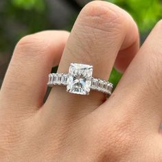 a woman's hand with a diamond ring on top of her finger and an engagement band