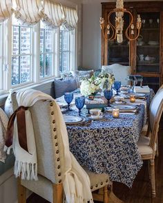 the dining room table is set with blue and white dishes, candles, and flowers