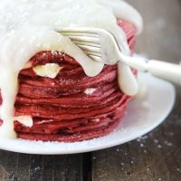 a stack of pancakes covered in icing on a white plate with a fork sticking out of it