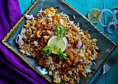 a plate filled with rice and vegetables on top of a purple table cloth next to silverware