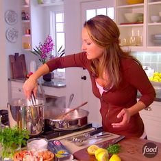 a woman standing in front of a counter filled with food and cooking utensils