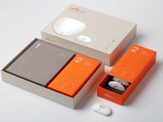 an orange and grey box with two earphones in it, next to another one