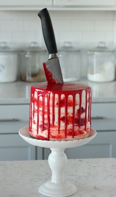 a red and white cake sitting on top of a table with a knife stuck in it