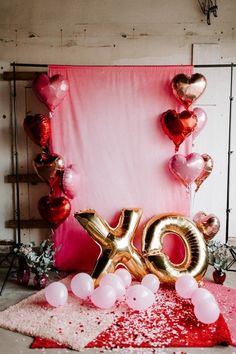 balloons and streamers are on the floor next to an xo balloon arch with heart - shaped balloons