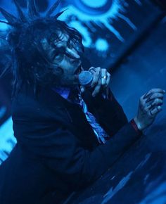 a man with long hair on stage singing into a microphone