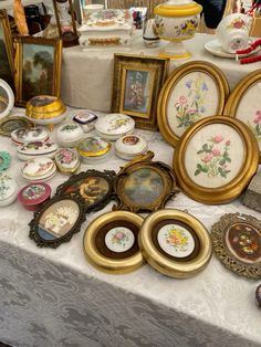 a table topped with lots of framed pictures