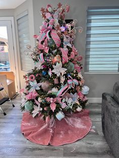 a decorated christmas tree with pink and blue decorations on it's top, in a living room