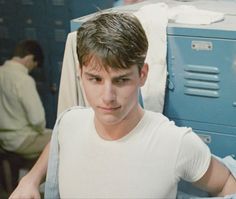 a young man standing in front of lockers with his hands on his hips and looking at the camera