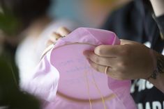 a person holding a pink paper bag with string