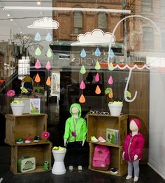 two dolls are standing in front of a store window with raindrops hanging from the windows