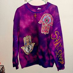 My Daughter Made This Sweatshirt! At No Additional Cost If You Want She Said She Will Add Rhinestones To The Yellow Cross On The Neck Area - The Rhinestones Will Be Clear & They Will Stay On. We Have The Ones For Fabric With Fabric Glue. And On The Back, It Just Has The Hamsa Hand The Arms Say Wake Up, Stay Sleep On Each Arm And Blue And Yellow. She Wants To Put Something In Either Fabric Paint Or The Glitter Letters. If We Did The Glitter Letters I Think It Would Be Cute She Said She Would Make Purple Relaxed Fit Sweatshirt With Graphic Print, Carhartt Hoodie Woman, Hamsa Sweater, Pink Long Sleeve Hip Hop Sweatshirt, Purple Relaxed Fit Graphic Print Sweatshirt, Purple Graphic Print Crew Neck Sweatshirt, Purple Hooded Sweatshirt With Graphic Print, Pink Sequined Crew Neck T-shirt, Carhartt Hoodie