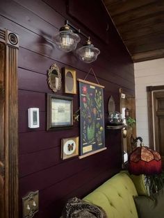 a living room with purple walls and pictures hanging on the wall, along with green couches