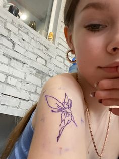 a girl with a small tattoo on her arm looking at the camera and holding her hand up to her face