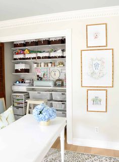 a white table and some shelves with pictures on the wall behind it in a room