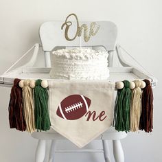 a cake sitting on top of a white chair next to a football themed table runner