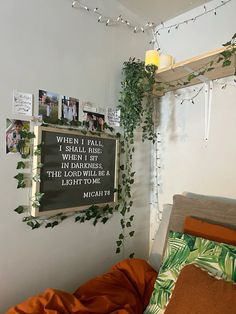 there is a bed with an orange comforter on it and some plants growing up the wall