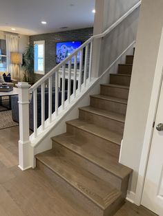 a living room filled with furniture next to a white stair case on top of a hard wood floor